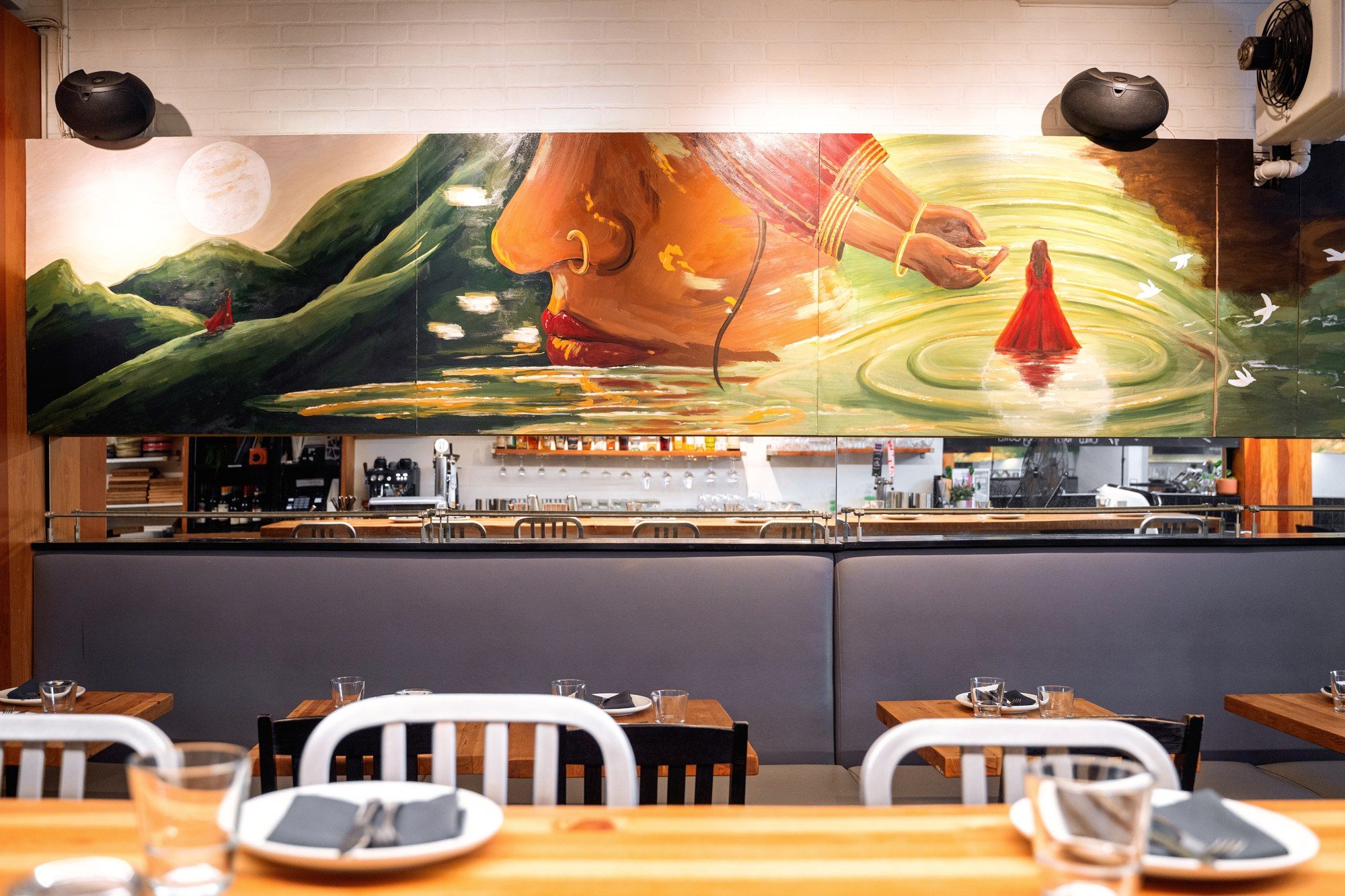 Full length of the painted artboard above the banquette at UNA Pizza + Wine on 17th Avenue, showing a woman in profile, a hand releasing something into water and a figure in a boat