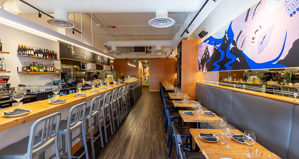 Uprooted mural interior view at UNA Pizza + Wine Bridgeland, full restaurant perspective showing mural scale above dining area, KINN Studios Calgary