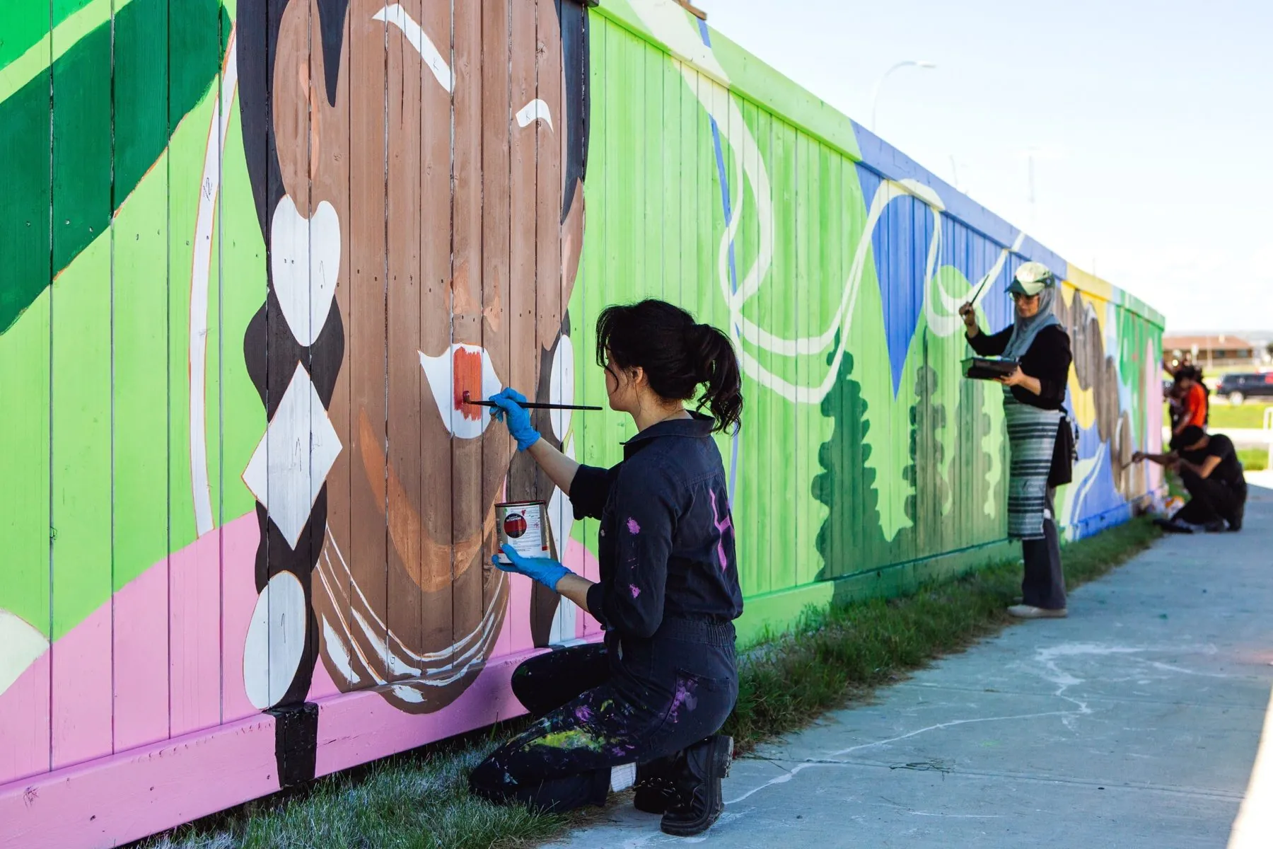 Community members painting Vibrance in Diversity mural, designed experience Calgary